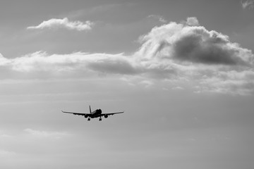 an airplane flying in the sky with cloud in monochrome