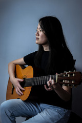 young beautiful asian woman playing guitar