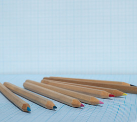  Wooden pencils with colored leads on blue squared paper. Copy space for text.
