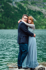 young couple on a walk near the lake surrounded by the mountains