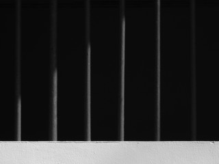 metal fence of prison on white concrete wall