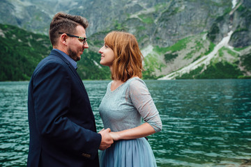 young couple on a walk near the lake surrounded by the mountains