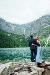 young couple on a walk near the lake surrounded by the mountains