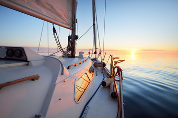 White yacht sailing after the rain at sunset. Close-up view from the deck to the bow. Clear blue...