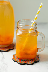 Orange fresh fruit beverage in the glass jar on the summer white background