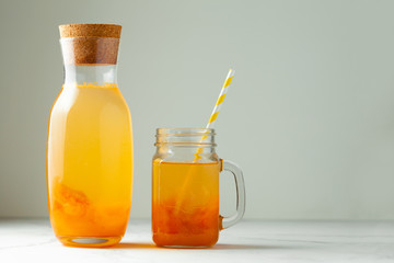 Orange fresh fruit beverage in the glass jar on the summer white background