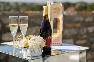 A bottle of champagne two glasses and a bouquet of flowers on the table for lovers, selective focus