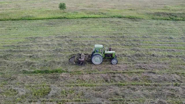 tractor with tedder collects hay in one line