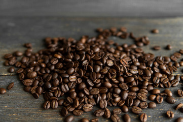 Roasted arabica coffee beans scattered on a wooden table. Fresh coffee beans.