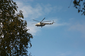 Fototapeta na wymiar helicopter in the blue sky above the trees