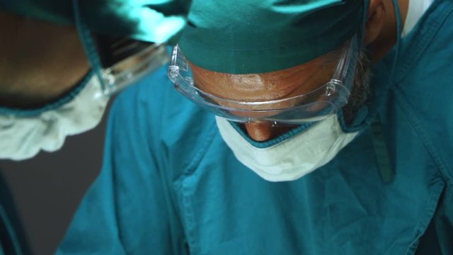 Close up team of surgeons performing an operation in hospital operating theater.