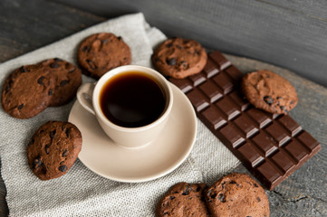 Coffee cup with cookies and chocolate on wooden table background. Mug of black coffee with...