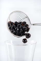 Making bubble tea, scoop and pour cooked brown sugar flavor tapioca pearl bubble balls into cup on white wooden table background, close up, copy space.