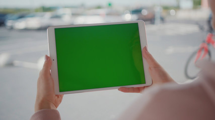 Close up hands woman using tablet device computer with green screen outdoors in street at sunlight horizontal bloom message pad technology chroma key female digital girl app chat finger mock up