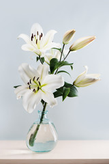 Bouquet of beautiful white lilies in vase on the table.