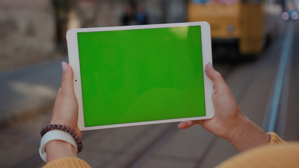 Close up hands woman using tablet device computer with green screen outdoors in street at sunlight horizontal bloom message pad technology chroma key female digital girl app chat finger mock up