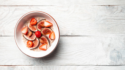Healthy food background with homemade oatmeal and fresh berries for healthy morning breakfast figs, rtrawberries and chia seeds and nuts. top view, copy space. Banner