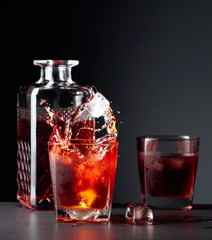 Pieces of ice fall into a glass of whiskey.