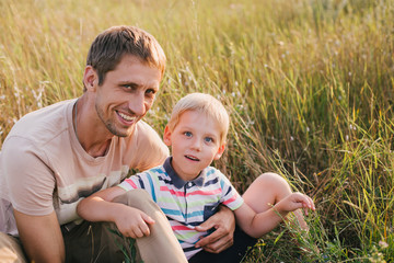 Fototapeta premium Happy young father and his little son in a field at sunset.