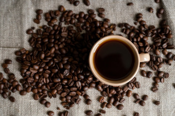 Fototapeta na wymiar Coffee cup with roasted coffee beans on linen background. Mug of black coffe with scattered coffee beans. Fresh coffee beans.
