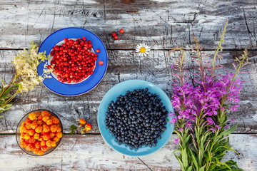 Freshly picked wild Estonian berries such as Cloudberries, Blueberries and Wild Strawberries on a rustic wooden table,

