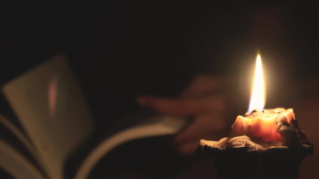 Young woman reading by candlelight in the dark, Education concept