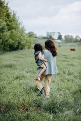 Portrait of hipster mother with daughter in her arms in the field. The family is having fun together