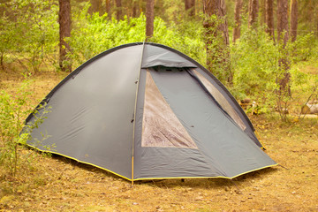 green tourist tent for two people stands in the forest Russia