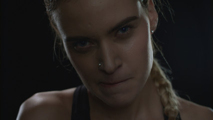 Fototapeta premium Aggressive woman biting lips looking to camera on black background