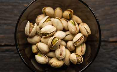 Pistachios in a small plate on a vintage wooden table. Pistachio is a healthy vegetarian protein nutritious food. Natural nuts snacks.