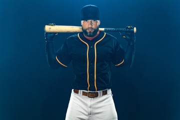 Baseball player with bat on dark background. Ballplayer portrait.