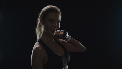 Obraz premium Sport woman smiling with dumbbell on shoulder in gym. Fitness model smiling