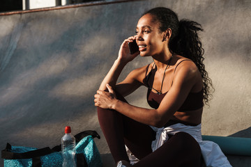 Obraz premium Photo of smiling african american sportswoman talking on mobile phone