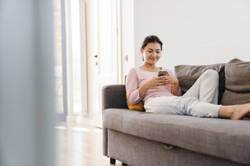 Pretty asian girl using smartphone on the couch