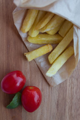 Fresh fried french fries with tomatos on wooden background