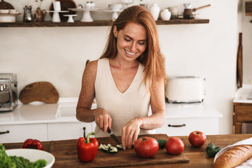 Smiling attractive young woman making a salad