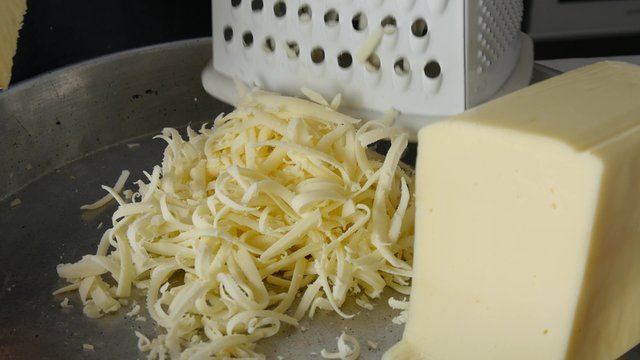 Chef grating cheese for pizza, close up