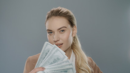 Young business woman holding cash money. Rich girl hold dollar money near face
