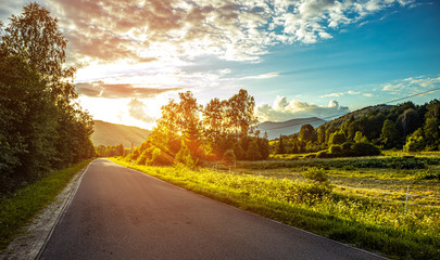 Bieszczady Poland. Road in the mountains at sunset in summer. Sun rays at sunset over the road.