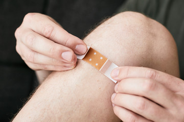 Junge, der sich ein Pflaster auf das Knie klebt