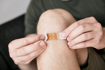 Junge, der sich ein Pflaster auf das Knie klebt