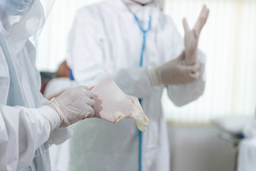Doctors put on protective gloves and suit mask before Patient treatment in hospital patient in the control area.  Covid-19 and Coronavirus disease.