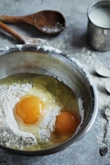 flour and eggs in a bowl on a concrete background