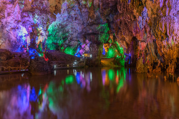 Colorful stalactites and water reflections in the cave