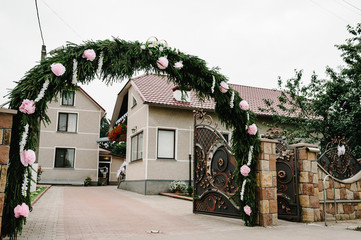 The decorated arch of flowers and the entrance gate, the courtyard with the house. Morning preparations for a wedding day.
