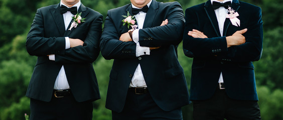 Wedding portrait groomsmen and groom stand on nature. Young friends groomsman. Cheerful friends outdoors. Wedding day.