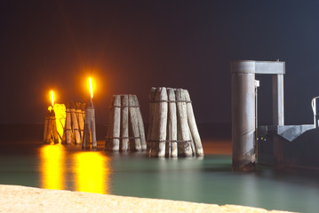wooden poles for mooring large boats, illuminated in the night