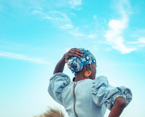 Une Femme Noire De Dos Dans Une Robe Bleue Avec Un Foulard Sur La Tête Sur  La Plage Lève Les Mains Au Ciel Africa Wall Mural | Afri-Orelienfly