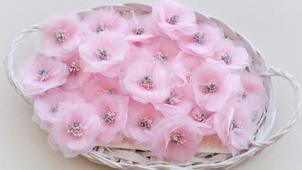 Artificial handmade flowers made out of beautiful organza and tulle fabric texture in soft pink color