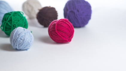 Colorful yarn balls arranged on a white surface.  A variety of colors and sizes of yarn ready to be knit or crocheted into a number of different items.  